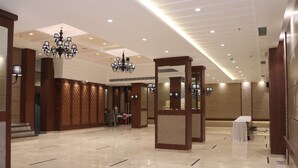 Un vestíbulo espacioso con suelo de mármol pulido, un candelabro imponente y un mostrador de recepción.
