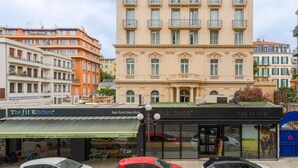 Un immeuble à plusieurs étages, de style architectural classique, doté d’une entrée centrale surmontée d’une arche décorative et de nombreuses fenêtres.