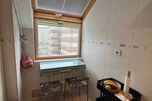 Un petit coin cuisine avec une fenêtre, un radiateur et une table avec des chaises.