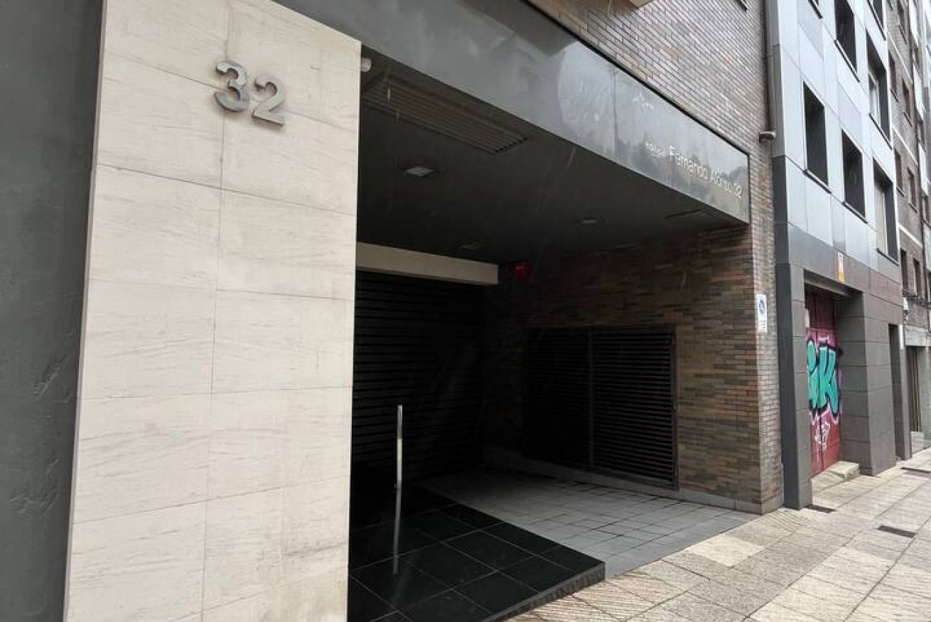 Entrada de un edificio con un letrero con el número '32', un juego de puertas dobles y unos escalones que conducen a la entrada.