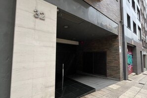 Entrada de un edificio con un letrero con el número '32', un juego de puertas dobles y unos escalones que conducen a la entrada.