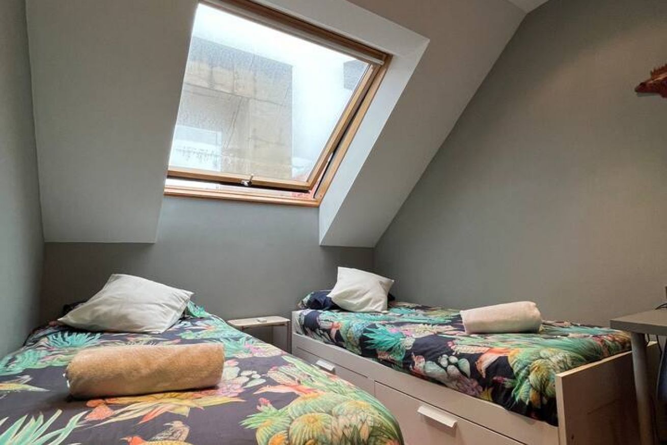 Un dormitorio con dos camas individuales, un tragaluz y un escritorio pequeño.