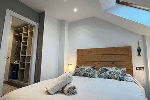 A bedroom with a bed, a wooden headboard, a closet, and a skylight.