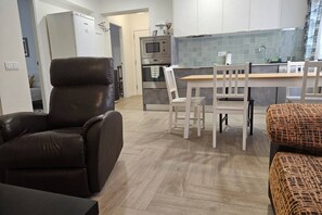 Una cuina moderna amb microones, forn i zona de menjador amb taula i cadires.