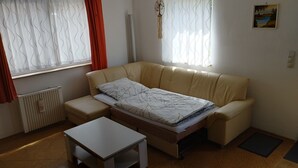 Une petite pièce agréable, avec un canapé beige, une petite table et un radiateur.