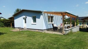 Une petite maison de plain-pied dotée d’un patio couvert.