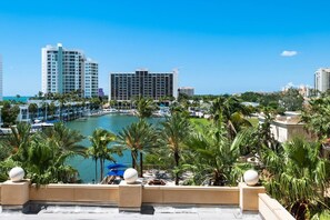 A marina with boats, a pool area with palm trees, and high-rise buildings in the background. - Resort Style Condo, Lanai, Waterview, Pool/Tennis (Siesta Key)