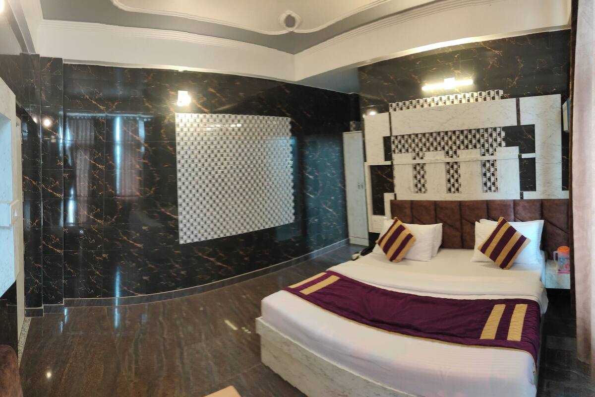 A modern bedroom with a large bed, dark marble walls, and a patterned headboard.