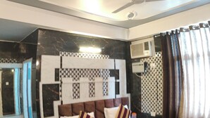 A hotel room with a large bed, a ceiling fan, a marble floor, and a window with curtains. - Hotel Sunshine (Reasi)