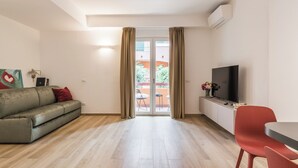 Una sala de estar moderna con sofá, televisión y comedor.
