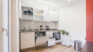 Una cocina moderna con armarios blancos, lavavajillas, horno y pileta.