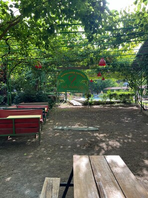 A park with a green sign, benches, and a picnic table. - Asmalı Köşk Pansiyon (Kumluca)
