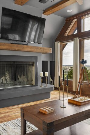 A modern living room with a fireplace, a mounted TV, and a chessboard on a wooden table.