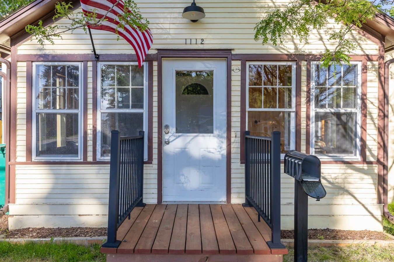 A house with a front porch, a mailbox, and an American flag.