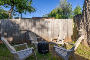 A backyard with a wooden fence, two Adirondack chairs, and a black Solo Stove backpack. - 1 block from Mainstreet! Hot Tub (Sturgis)