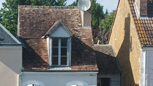 A two-story building with a gabled roof, white shutters, and a satellite dish. - The house by the water (Graçay)