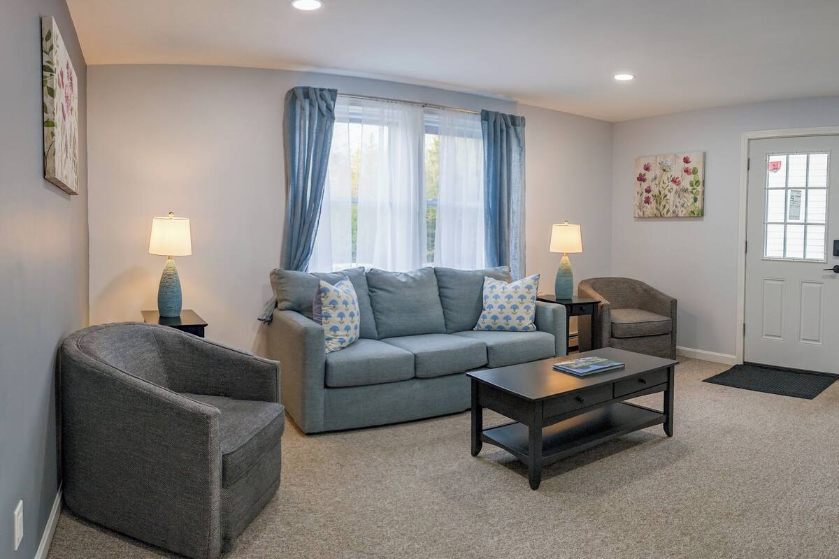 A living room with a grey sofa, two armchairs, a coffee table, and two lamps.