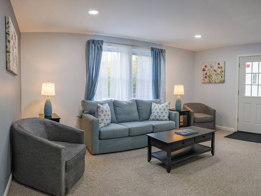 A living room with a grey sofa, two armchairs, a coffee table, and two lamps.