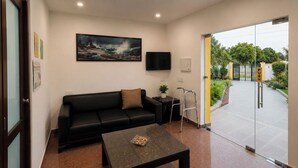 Una sala de estar moderna con un sofá negro, una mesa de centro, un cuadro y un televisor.