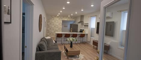 A modern living room with a sofa, coffee table, and a kitchen area with bar stools.