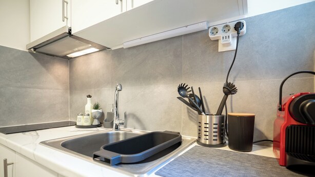 Una cocina moderna con un lavamanos doble, horno empotrado y cafetera.