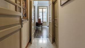 A hallway with doors on either side, a patterned rug, and a table with chairs in the center. - Amari Elegant Apartment by Wonderful Italy (Palermo)
