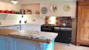 A kitchen with white cabinets, a marble countertop, a gas stove, and a dishwasher. - Beautiful country house at the entrance to the Crozon peninsula (Rosnoën)