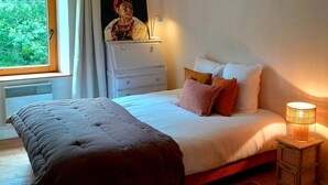 A bedroom with a bed, a nightstand, a dresser, a painting, and a window with curtains. - Beautiful country house at the entrance to the Crozon peninsula (Rosnoën)