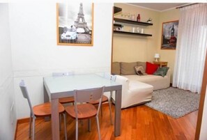Un petit espace de vie comprenant une table à manger, des chaises, un canapé et un tapis.