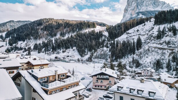 Un pueblo cubierto de nieve con edificios, una montaña y cielo despejado.