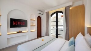 A modern hotel room with a large bed, a TV mounted on the wall, a wardrobe, and a built-in wardrobe with a mirror. - Onnea Villa by Lead (Canggu)