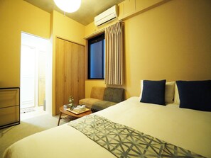 A hotel room with a bed, a desk with a tray of breakfast items, a wardrobe, and a window with curtains.