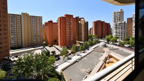 A high-rise building with multiple floors, a parking area, and a few trees. - PARQUE EUROPA (1 BEDROOM) (Benidorm)