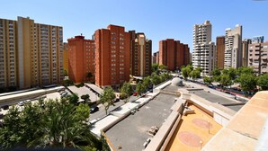 A high-rise residential building with multiple balconies, a parking area, and a clear sky. - PARQUE EUROPA (1 BEDROOM) (Benidorm)