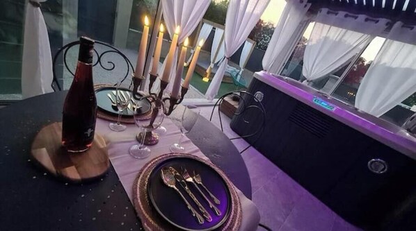 Enjoy a romantic dinner for two in this serene outdoor setting, complete with a wine bottle, fine china, and a warm candelabra.