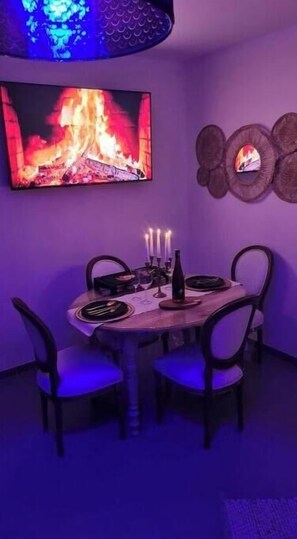 Enjoy meals with family and friends at this dining area, featuring a round table and comfortable seating for four, accompanied by a flat-screen TV and warm candlelight.