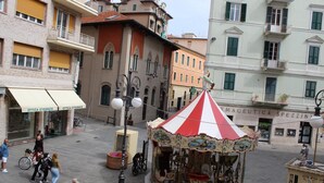 A carousel in a square with surrounding buildings, including a pharmacy. - I Remi del Prione by Le 5 Terre (La Spezia)