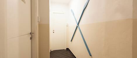 A hallway with a white door labeled "Bonassola," a blue and white wall, and a dark tiled floor.