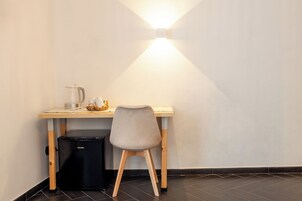 A compact workspace with a desk, chair, and a compact refrigerator.