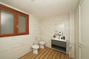 A modern bathroom with a wooden vanity, a toilet, and a bidet. - Casa Monte Cicogna PT-1 by Wonderful Italy (Moniga del Garda)