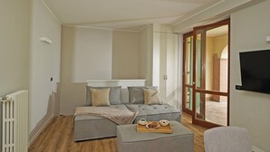 Une chambre moderne avec un canapé-lit, une petite table sur laquelle se trouve un plateau de nourriture et un téléviseur fixé au mur.
