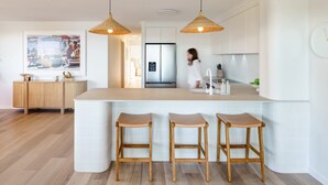 Une cuisine moderne dotée d’un îlot central, de deux suspensions et d’un réfrigérateur.