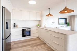 A modern kitchen with white cabinetry, a built-in oven, and a large island with a sink.