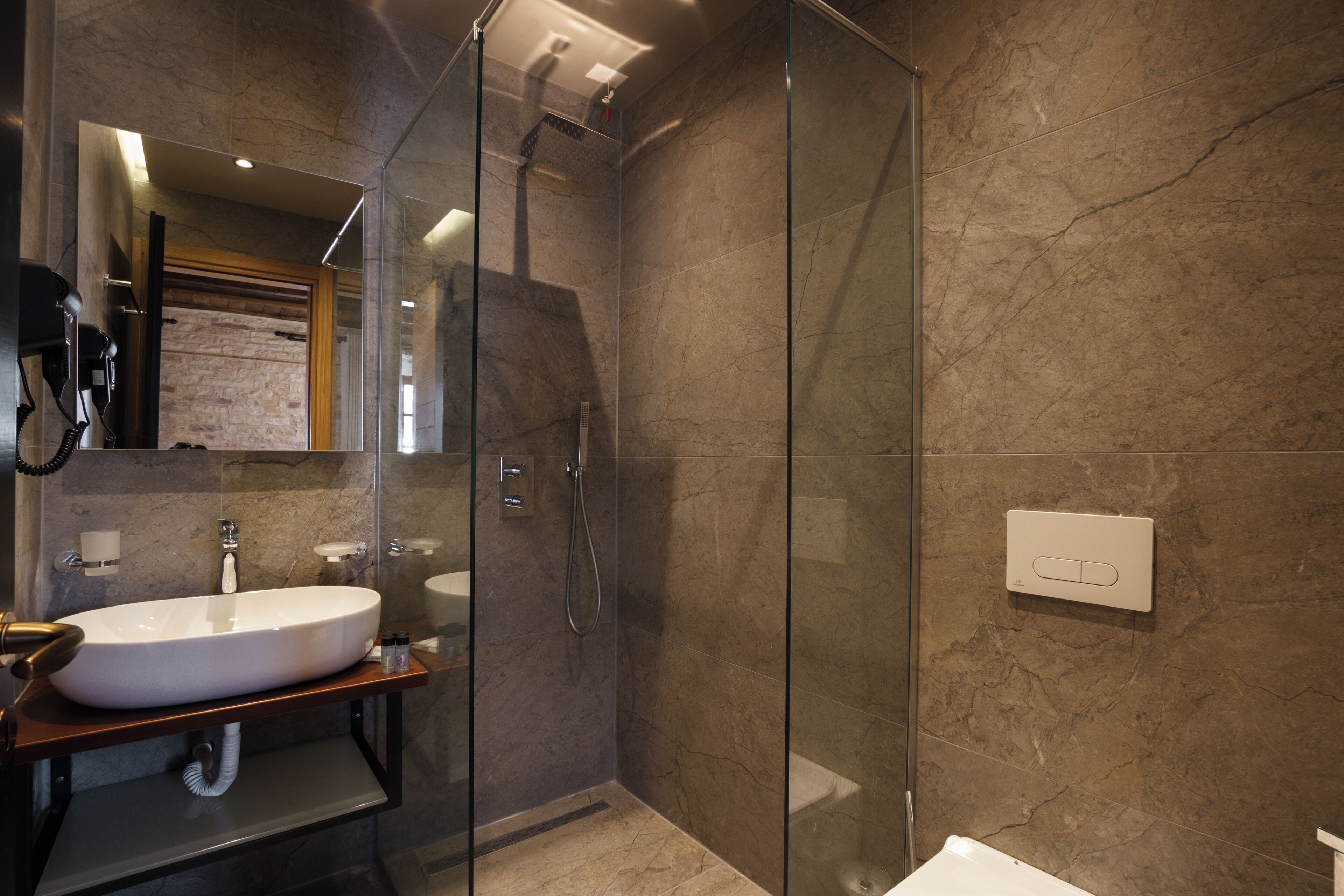 Un baño moderno con ducha de vidrio, un lavamanos grande y un espejo sobre el lavamanos.