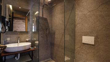 Un baño moderno con ducha de vidrio, un lavamanos grande y un espejo sobre el lavamanos.
