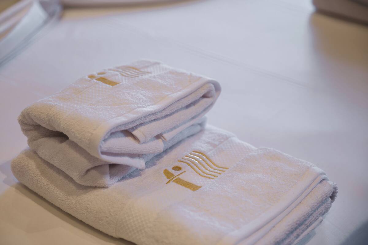A stack of folded towels with a gold emblem on a white surface.