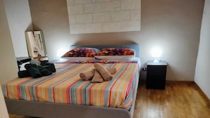 Een slaapkamer met een groot bed, een nachtkastje en een wandlamp.