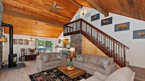 A spacious living area with a stone fireplace, a wooden ceiling, and a cozy seating arrangement.
