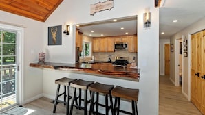 A modern kitchen with wooden cabinets, a central island with bar stools, and a sign above the island.