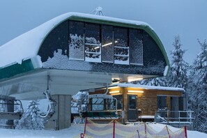 En snötäckt liftstation med en trähusliknande byggnad och ett överbyggt väntområde.